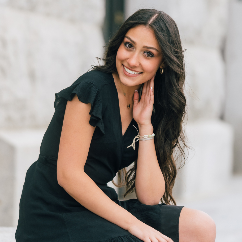 Girl Sitting On Step Outside Of Building Smiling