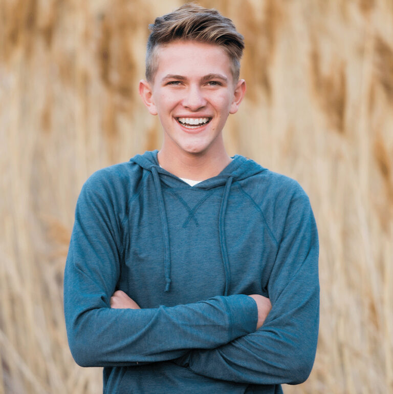 Smiling Boy Standing In Front Of Field Of Wheat