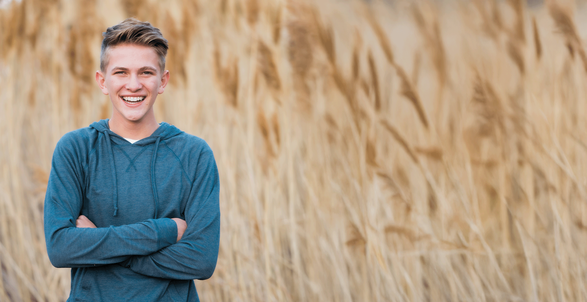 Smiling Boy Standing In Front Of Field Of Wheat